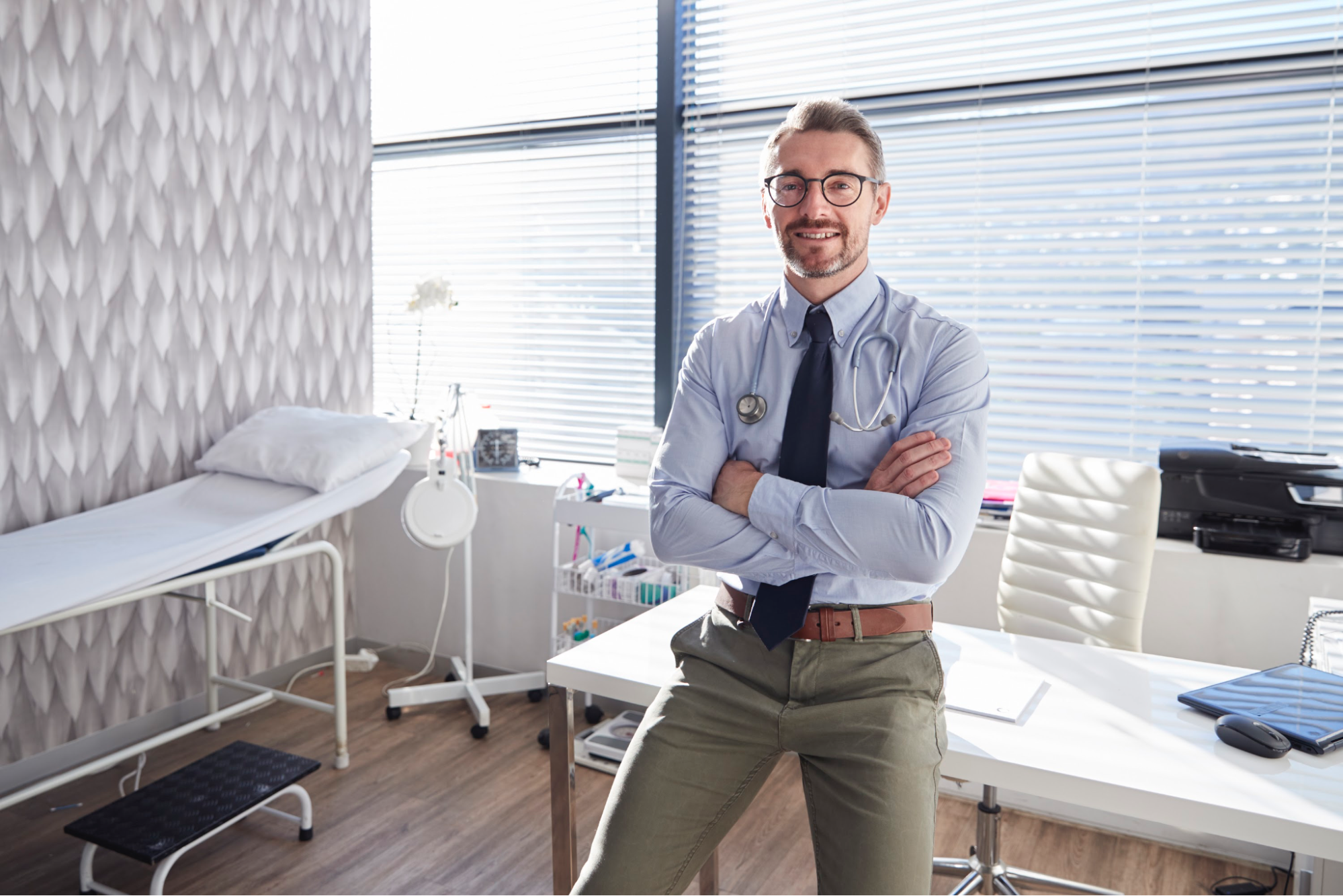 A male doctor leaning on a desk.