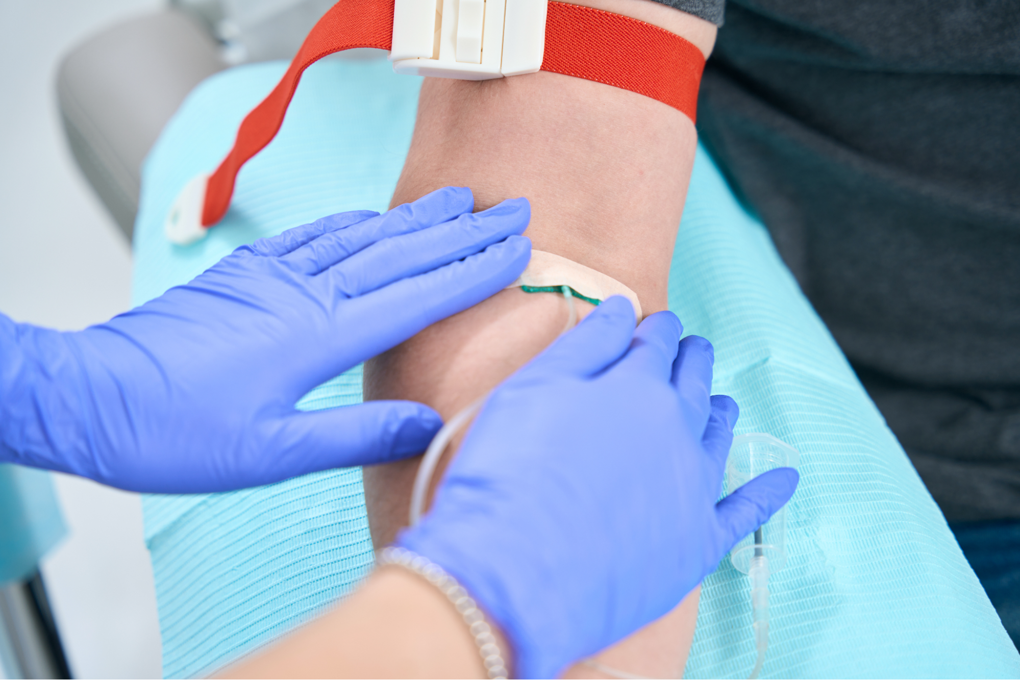 Gloved hands securing an IV needle in a man’s arm.