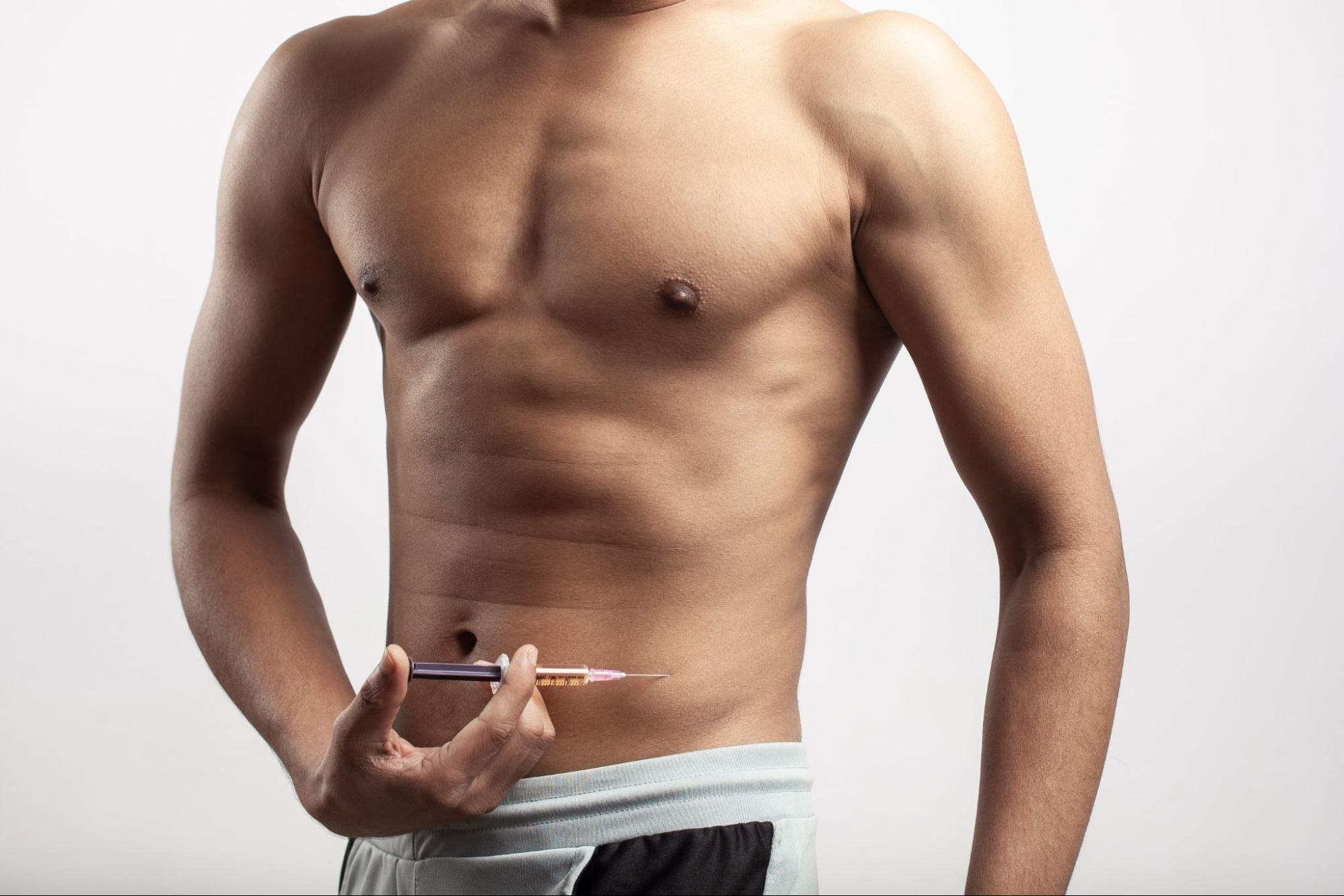 Shirtless man holding an injection. 