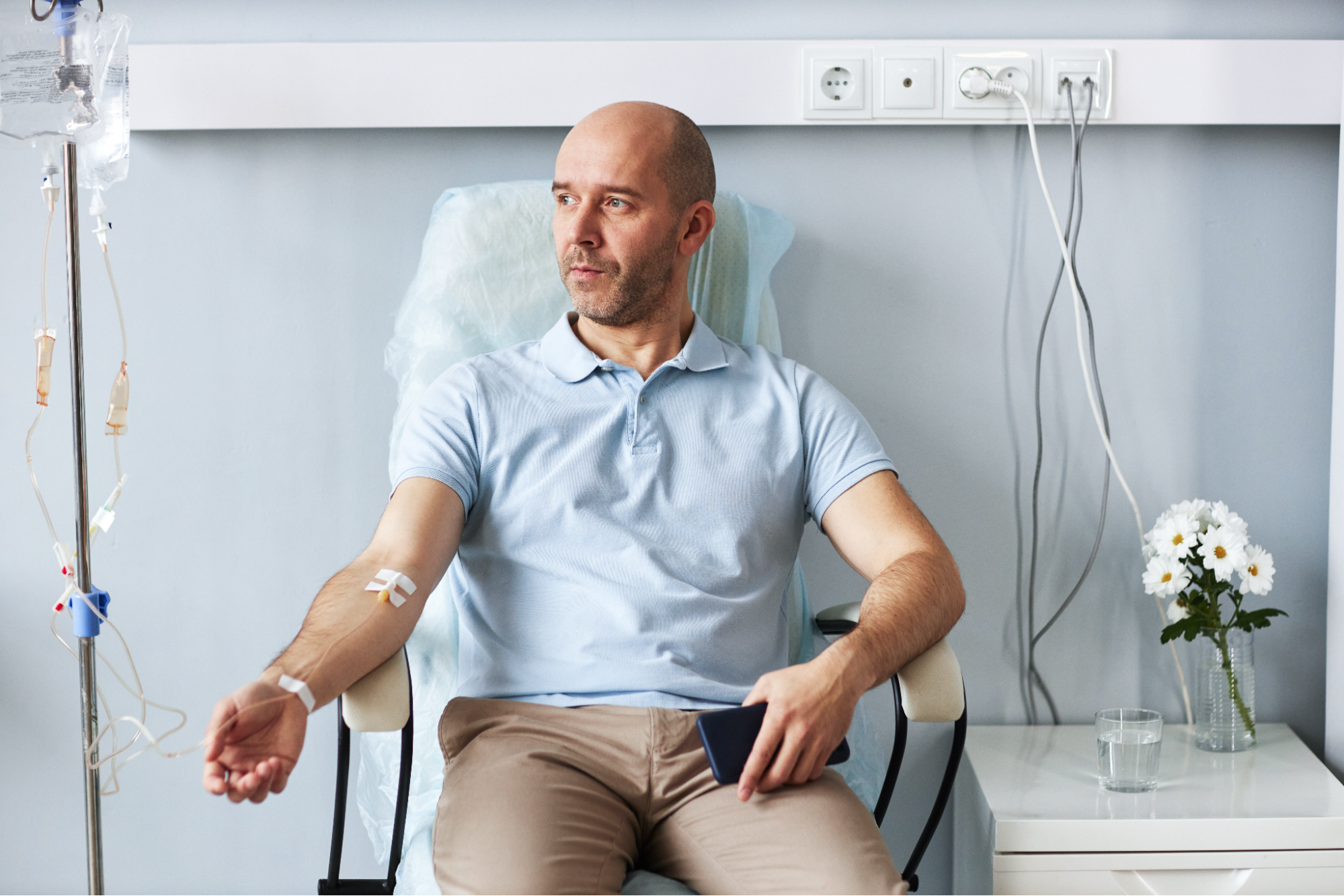 A man sitting in a chair receiving an IV treatment. 