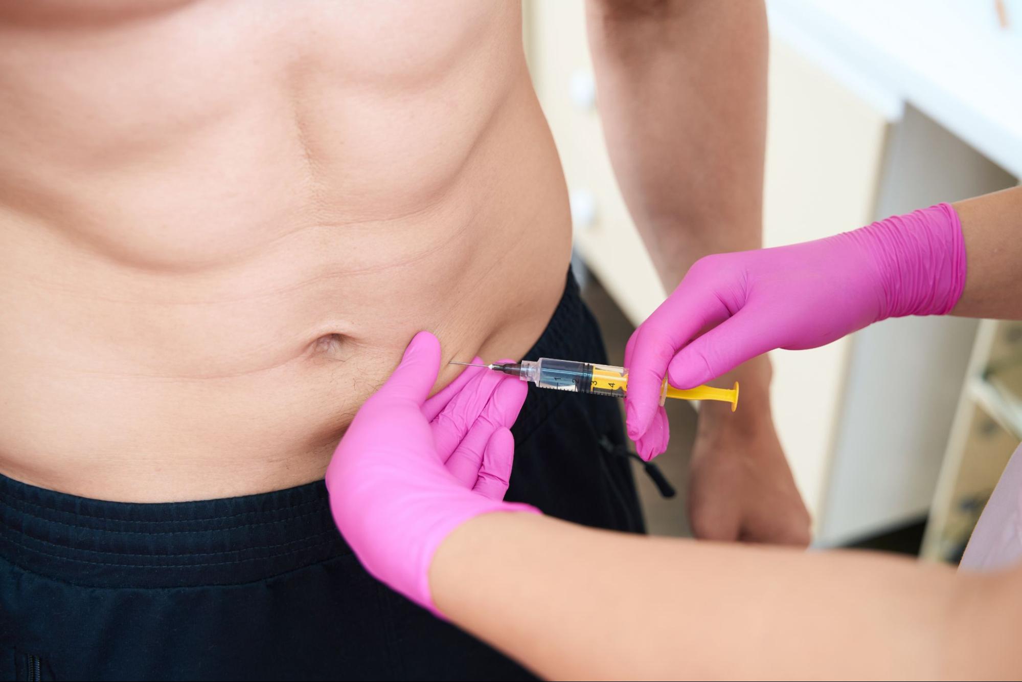 A man is getting an injection on his stomach by a nurse.