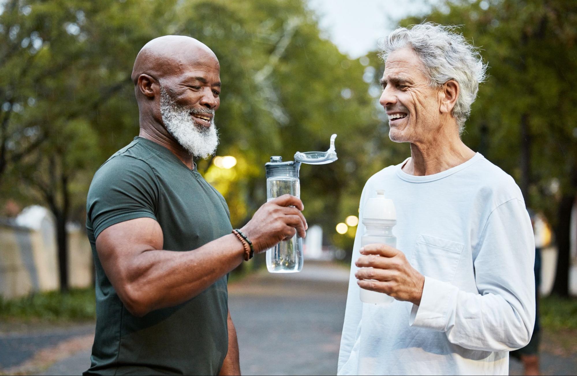 Two older men are drinking water after exercising.
