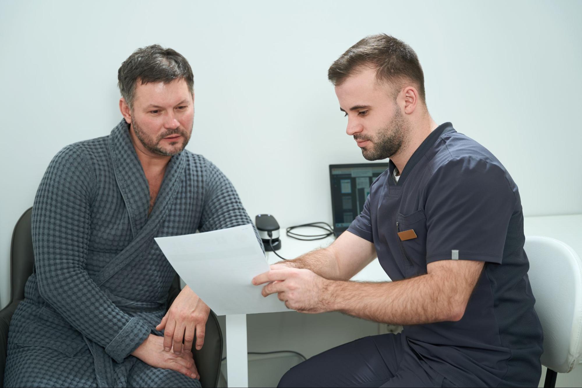 A man looks at results of a test with a men’s health clinic professional.