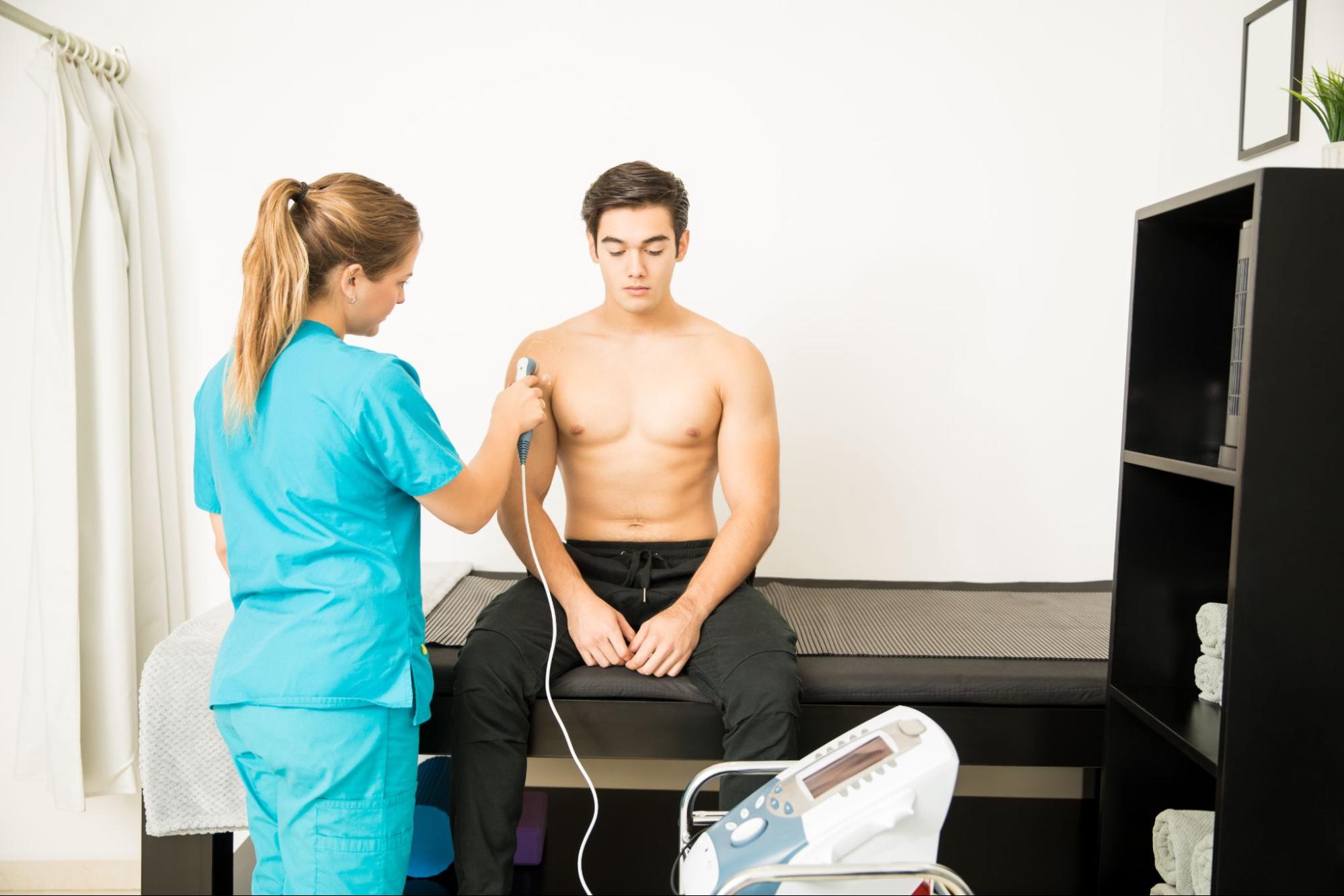A young athlete undergoes shockwave therapy from a medical professional.