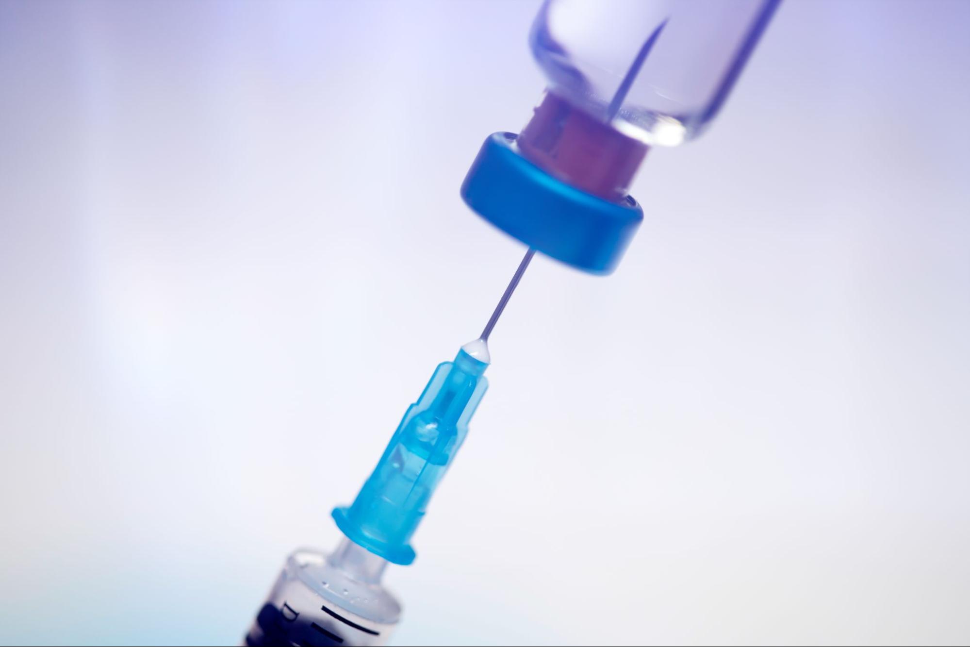 Closeup on a syringe in a vaccine bottle drawing out peptide therapy.