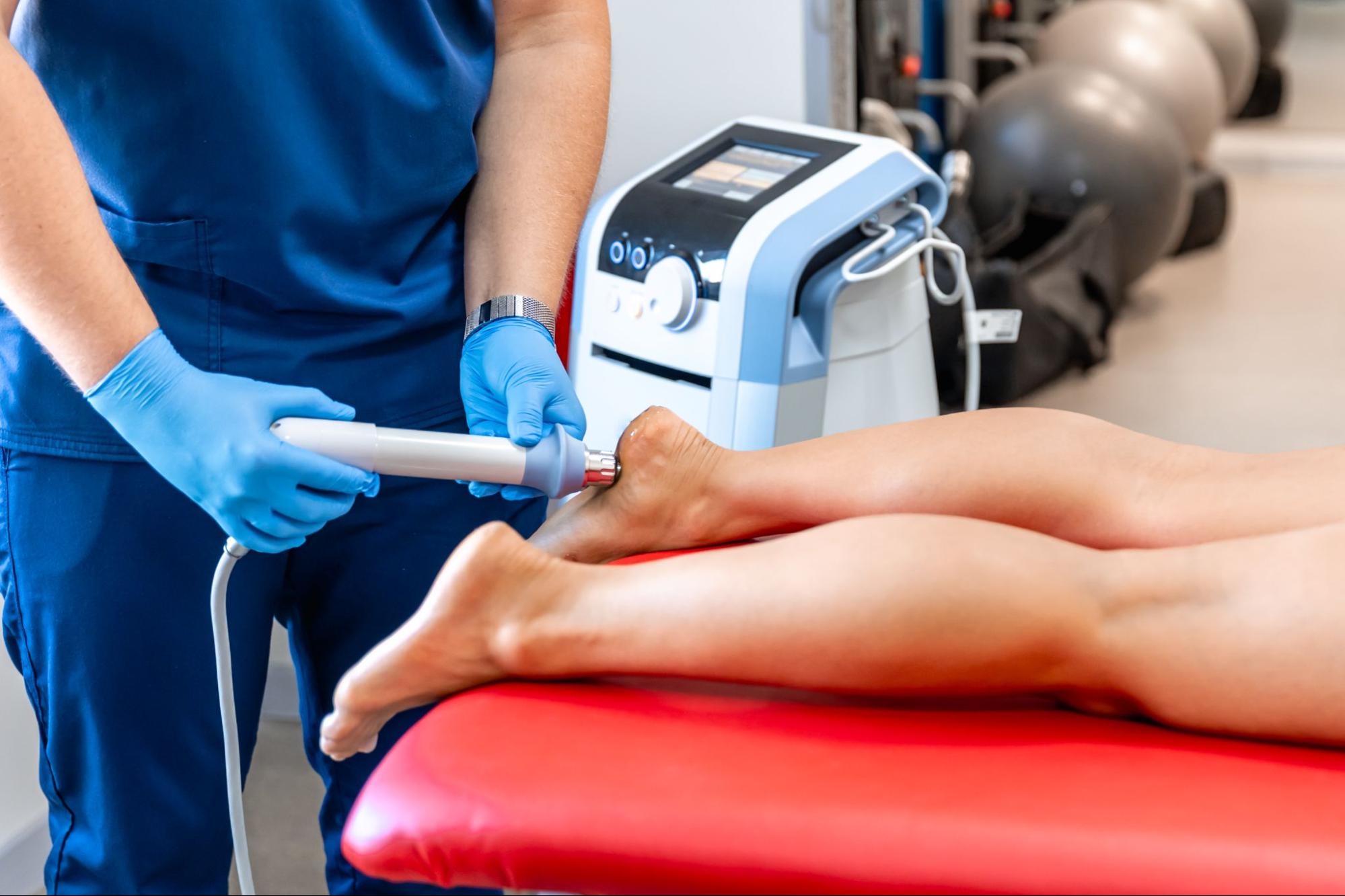 A physical therapist uses shockwave therapy to treat a patient’s foot discomfort.