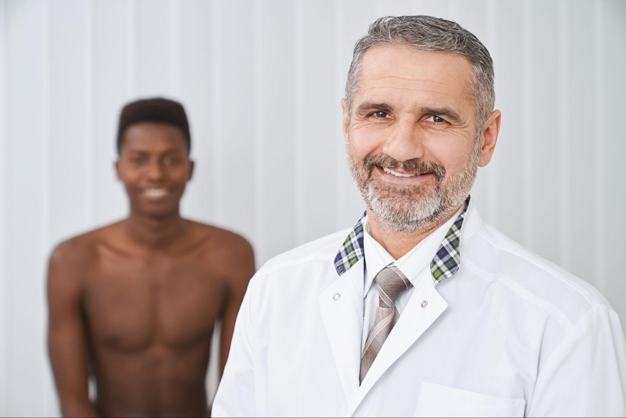 A medical professional from a men’s health clinic with his patient in the background.